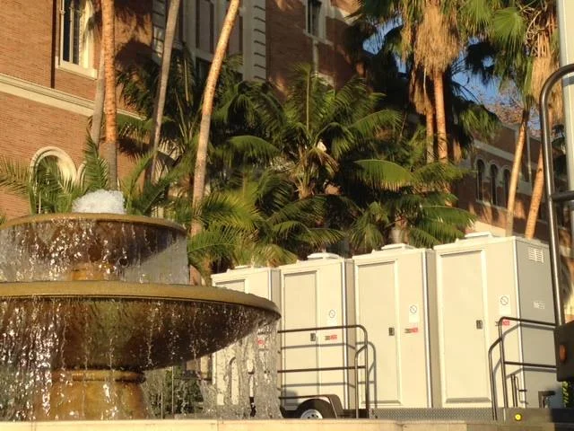 A VIP restroom trailer rental next to a flowing fountain.