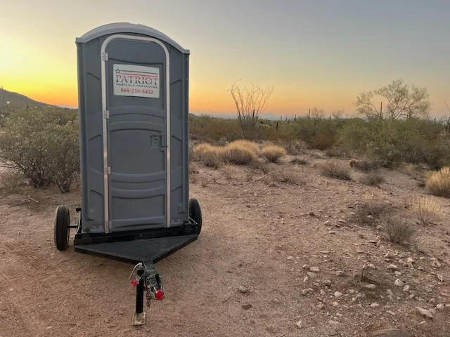 Patriot Portable Restrooms portable toilet on a desert job site at sunset