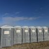 A picture of one of our wheelchair-accessible porta potty rentals alongside a line of standard porta potty rentals.
