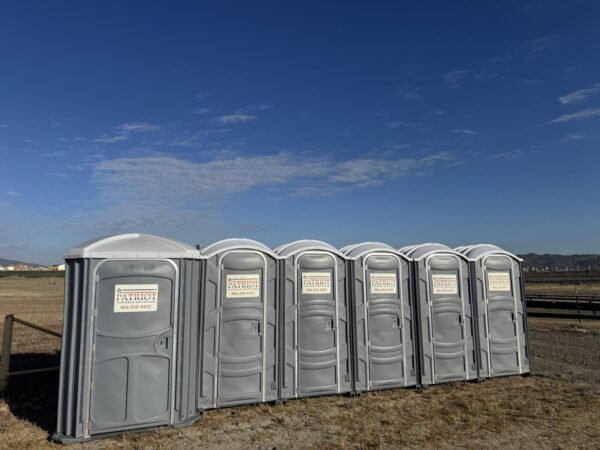 A picture of one of our wheelchair-accessible porta potty rentals alongside a line of standard porta potty rentals.