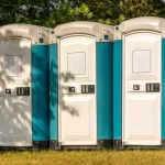 Outdoor portable restroom units placed on grass near trees for park or outdoor event use