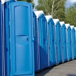 Row of blue portable toilets lined up outdoors for large events, construction sites, or public use